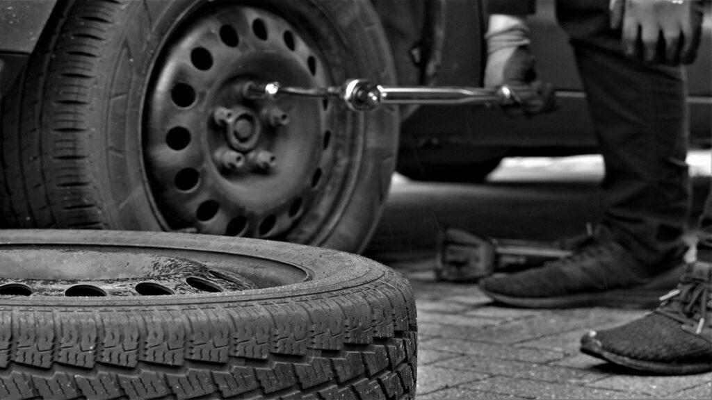 A person replacing a car tyre