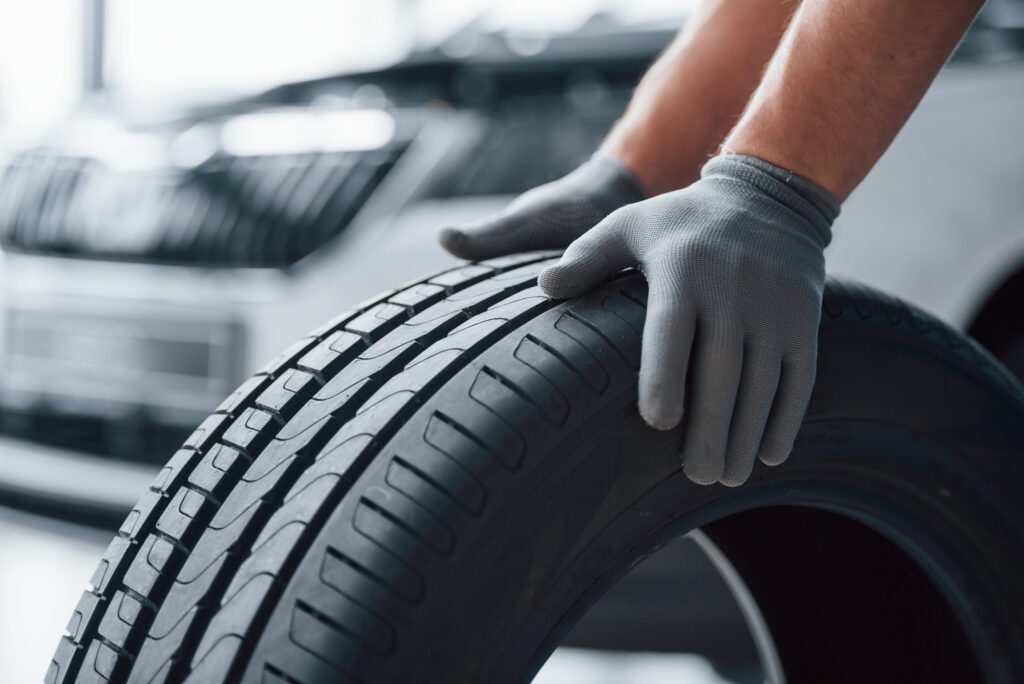 hands with grey gloves holing a tyre in a tyre fitter's garage