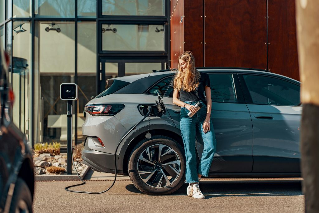 Woman charging an electric vehicle at a home EV charging station